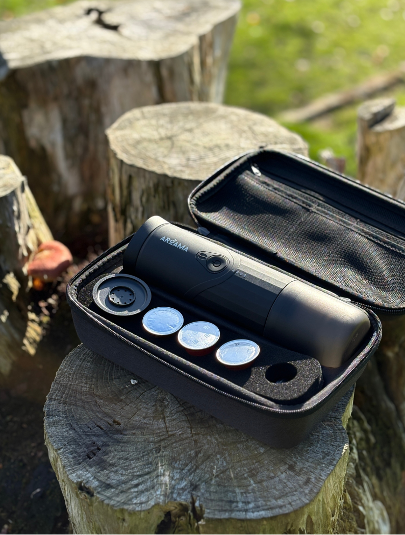 Black case with coffee machine on a wooden stump outdoors
