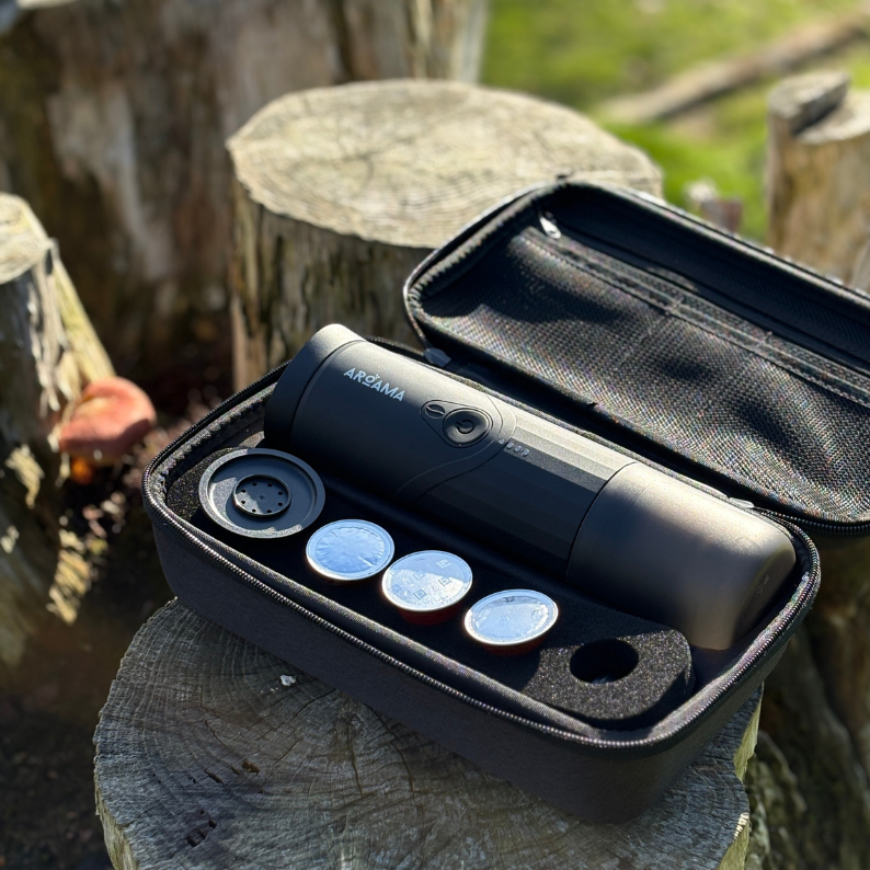 Black case with coffee machine on a wooden stump outdoors