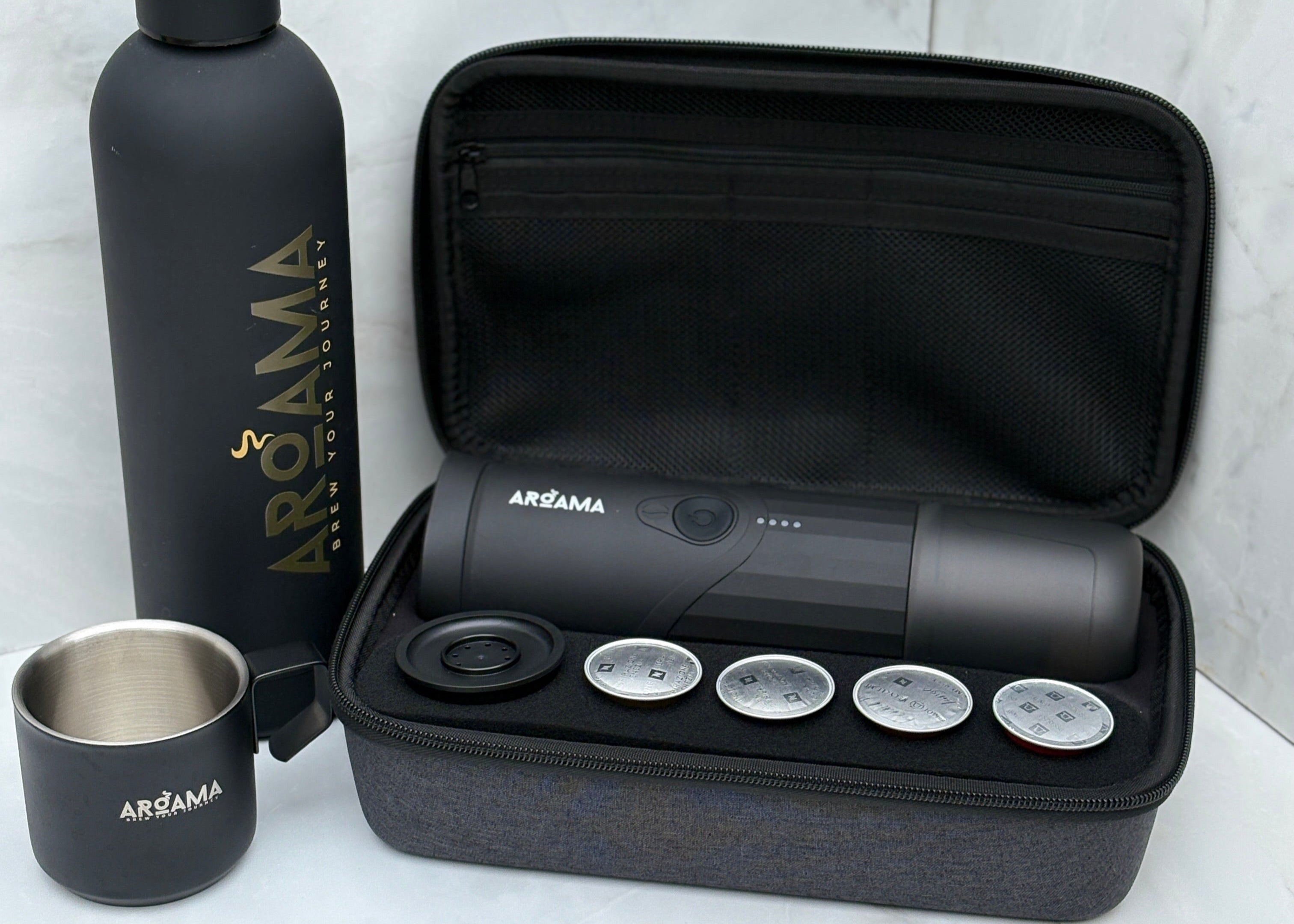 Aroma travel coffee kit with black water bottle, coffee maker, and accessories on a white background