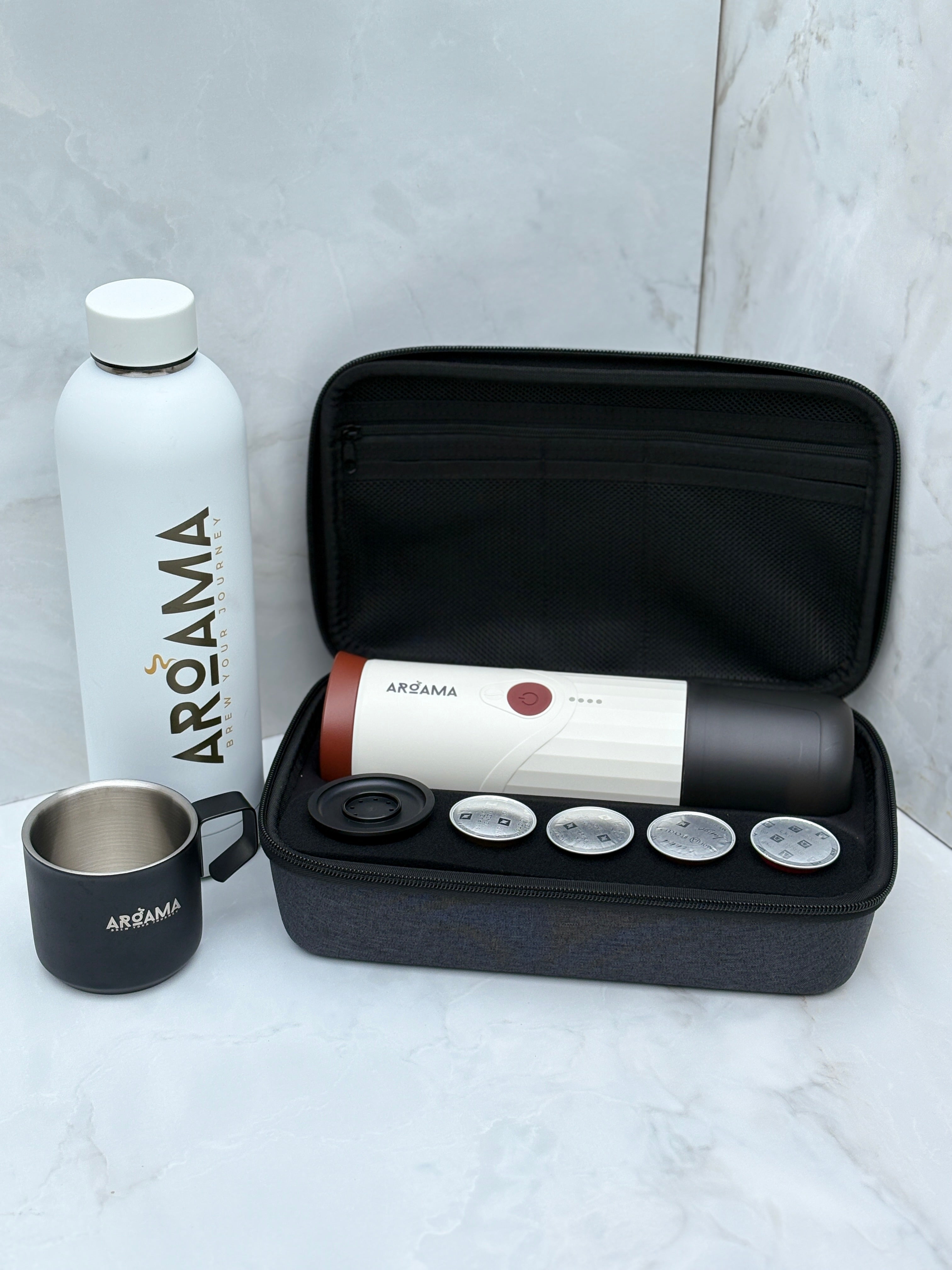Aroama travel coffee kit with a water bottle, mug, and travel case on a light gray background