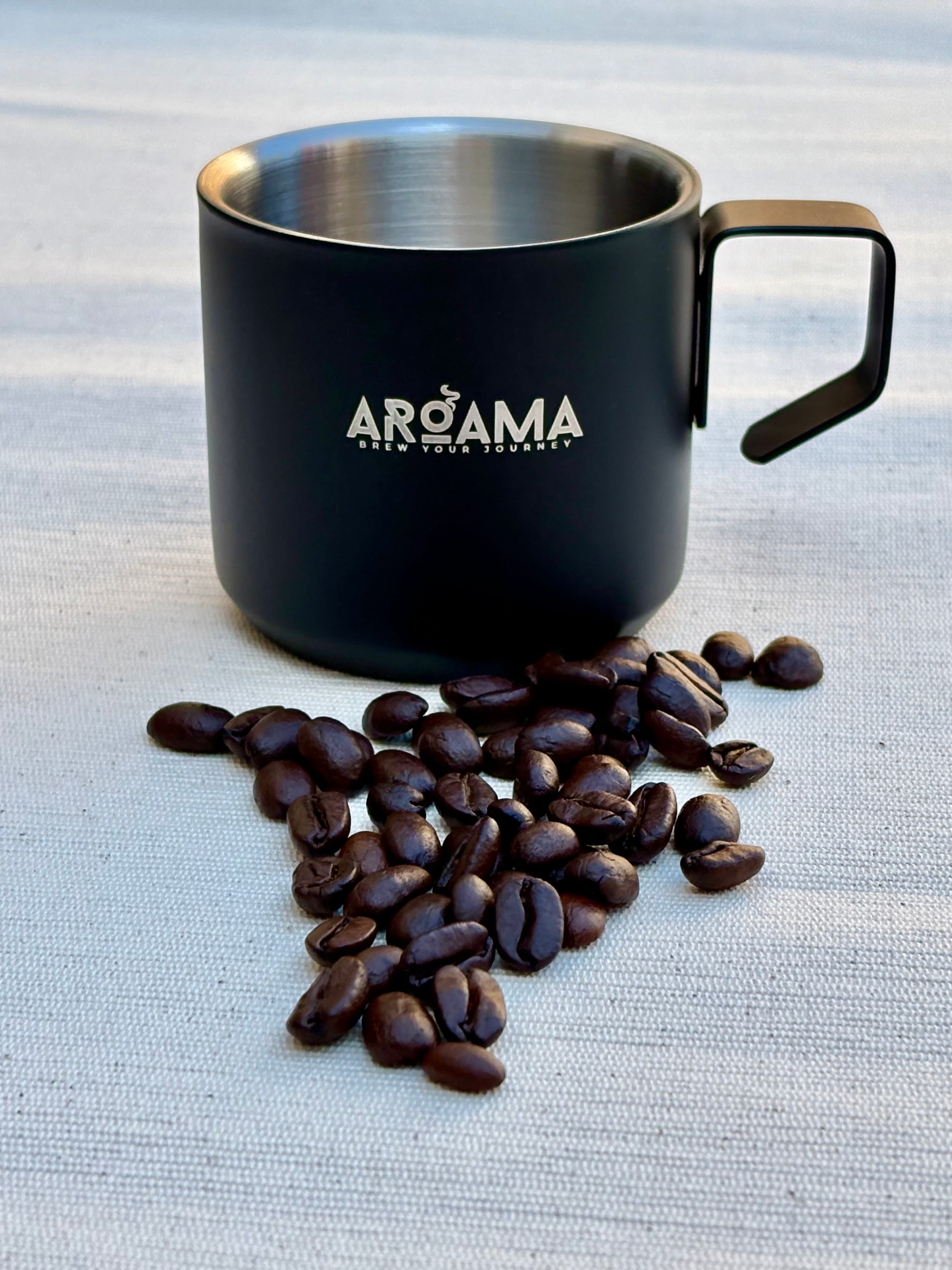 Black coffee mug with 'Aroma' branding next to coffee beans on a textured surface