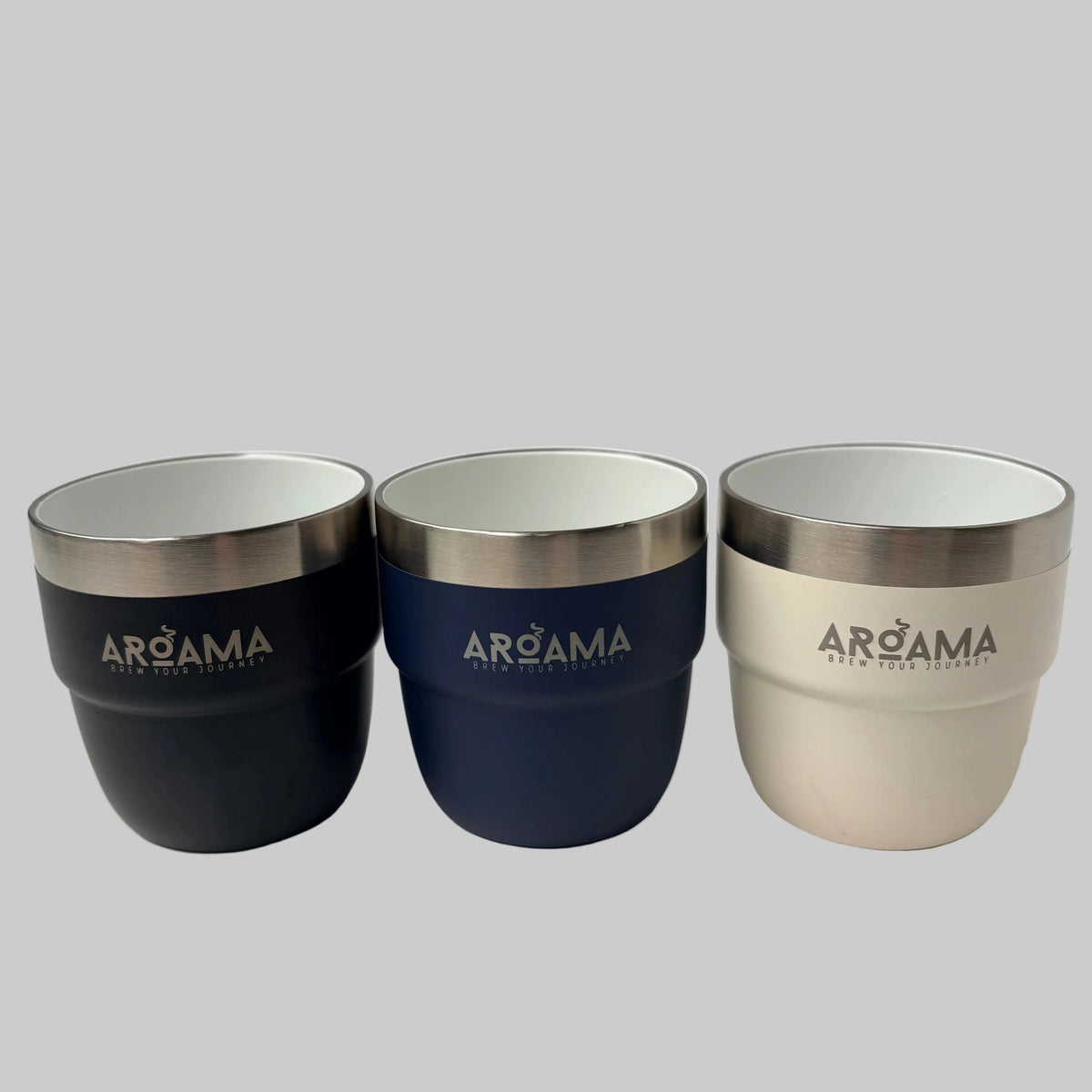 Three AROAMA insulated tumblers with stainless steel rims, shown in black, navy blue, and cream on a light marble surface.